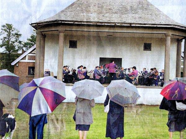 A brass band playing at the Kings Park bandstand, the audience under umbrellas
